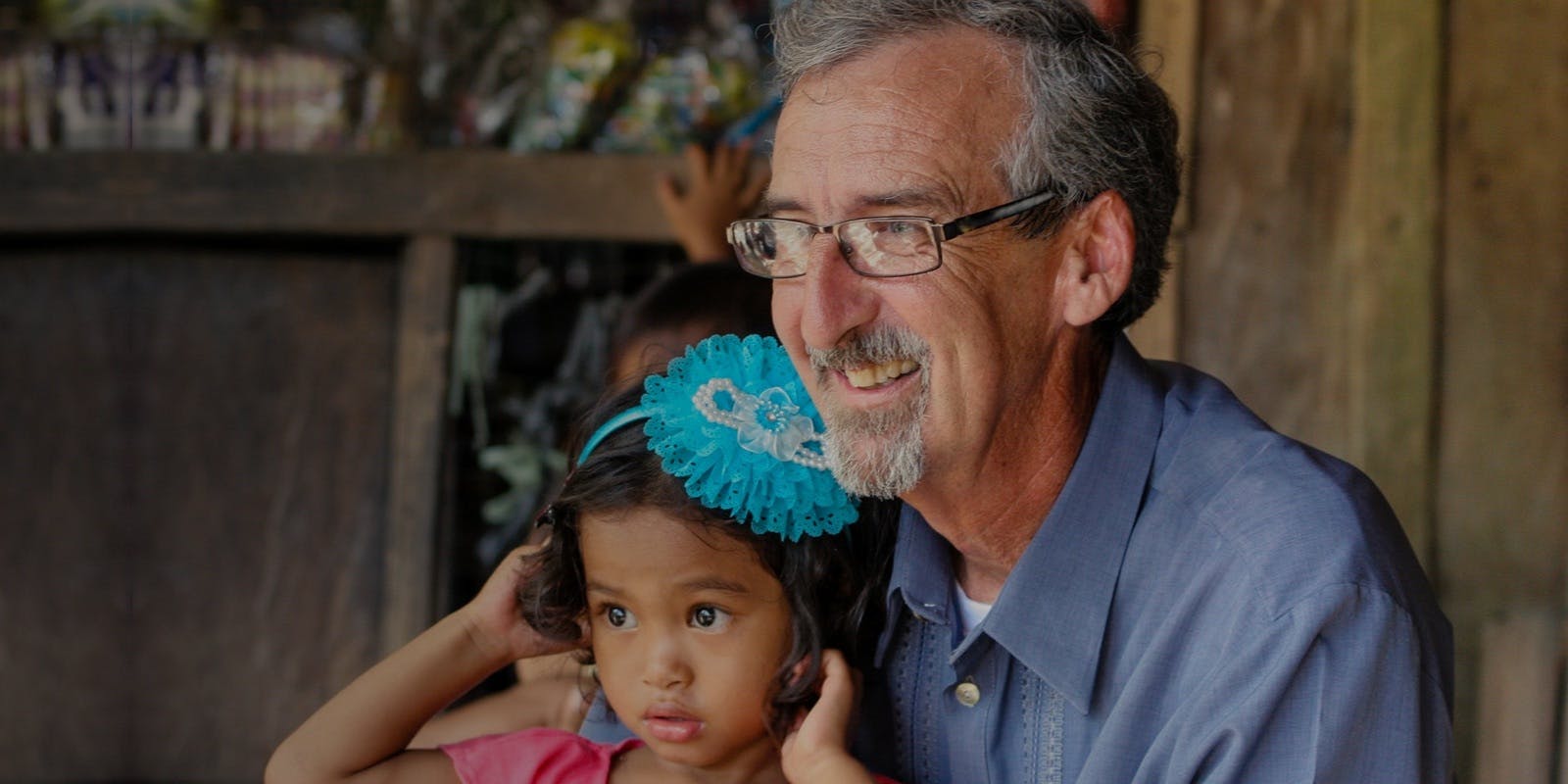 Older male smiling while holding a female child